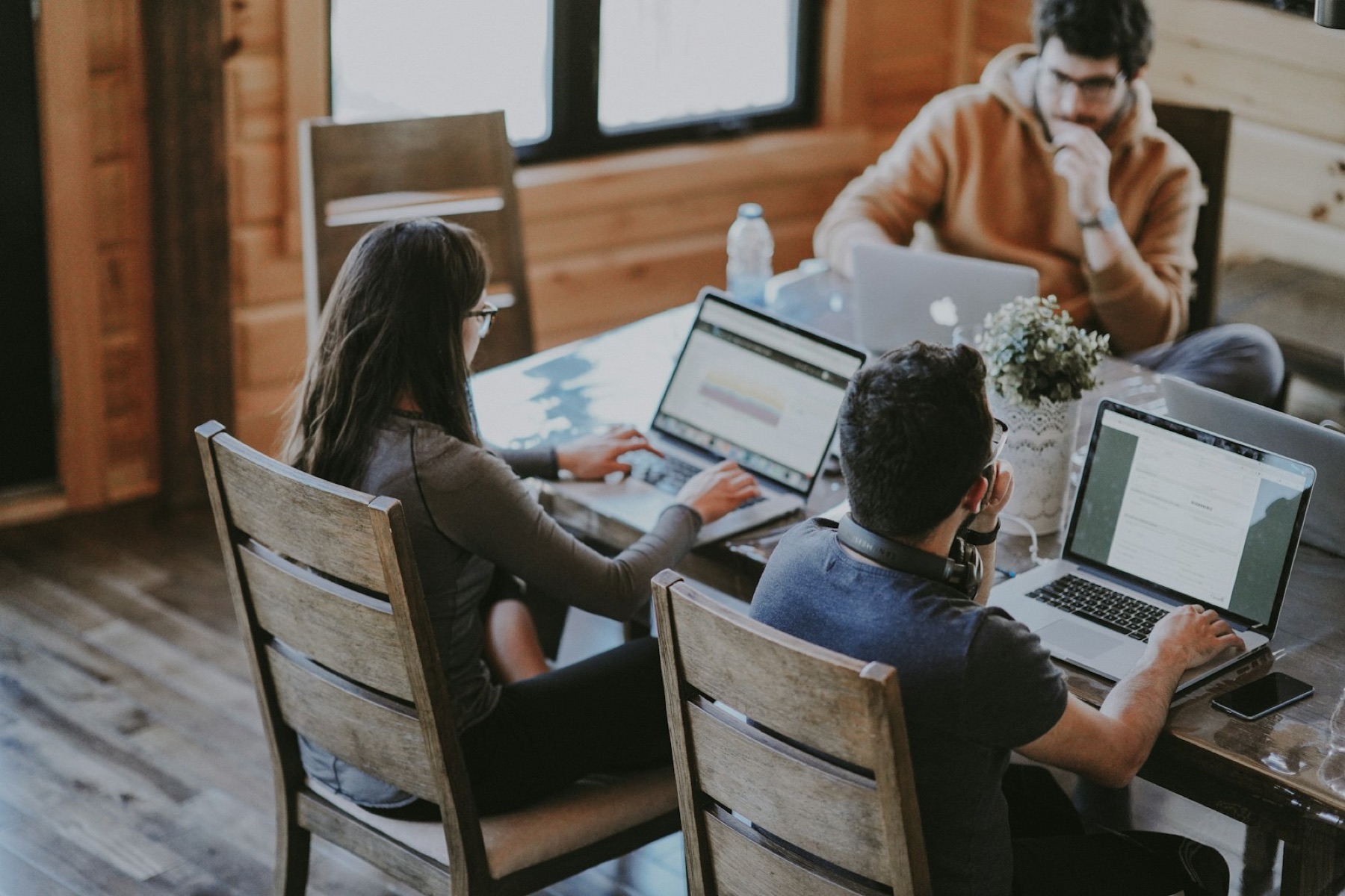 Three people working around one table, laptops open, the work in the middle